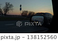 Sunset reflected in mirror. Orange horizon behind roadside vehicle. Peaceful country road under sunset glow 138152560