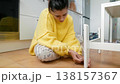 Woman Searches Floor. Young Woman On Tiled Floor Carefully Seeking Tiny Missing Item Near Furniture Leg 138157367