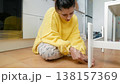 Woman Searches Floor. Young Woman On Tiled Floor Carefully Seeking Tiny Missing Item Near Furniture Leg 138157369