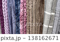 Variety of soft, fluffy, and colorful blankets hanging on display in a store, showcasing different textures, patterns, and hues for home decor and comfort, with price tags visible 138162671