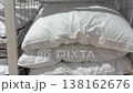 Multiple soft white pillows and folded duvets neatly stacked on metal shelves for sale in a department store, showcasing a wide selection of bedding options for home comfort and decor 138162676
