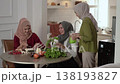 Gathered women smile while pouring vibrant green smoothies together 138193827
