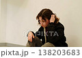 Upset adolescent girl sits alone in empty corridor with knees up and hands relaxed, taking pause to calm down and process emotions, concept burnout fatigue and emotional overload in youth. 138203683