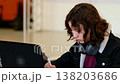 Focused teenage student sitting at table with laptop and notebook, resting headphones on neck after listening to educational video, concept concentration and study motivation. 138203686