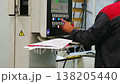 Factory worker operating industrial machinery control panel 138205440