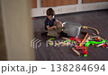 Young Boy Assembling Wooden Train Track, Scattered Colorful Pieces On Floor, Concentrated Play Near Basket, 138284694