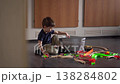 Young Boy Selecting Train Toys, Reaching Into Basket, Thoughtful Pause, Scattered Tracks On Floor, Warm Home 138284802