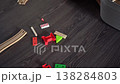 Colorful Wooden And Plastic Train Pieces On Dark Floor, Closeup Texture Near Gray Basket, Scattered 138284803