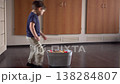 Young Boy Picking Toys Into Basket, Playful Tidy Movement, Hardwood Floor, Cabinet Backdrop, Warm Light 138284807