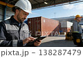 Worker using tablet at the huge storage place with containers. 138287479