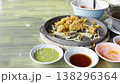Leftover crispy fried oyster omelette with bean sprouts on a hot plate. Multiple dipping sauce bowls in the foreground. Messy table after a traditional Thai meal at a street food restaurant. 138296364