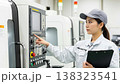 A worker inspects the control panel in a factory's NC-controlled manufacturing environment. A worker inspects the control panel in a factory's NC-controlled manufacturing environment. 138323541