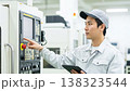 A worker inspects the control panel in a factory's NC-controlled manufacturing environment. A worker inspects the control panel in a factory's NC-controlled manufacturing environment. 138323544