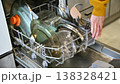 Person removes dirty dishes from dishwasher, preparing for kitchen organization 138328421