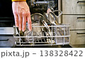 Hand removes drty dishes from dishwasher, kitchen setting with utensils visible 138328422