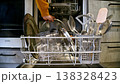 Person loading dirty dishes into dishwasher, kitchen setting with utensils visible 138328423