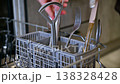 Hands placing utensils into a dishwasher basket for cleaning and organization 138328428