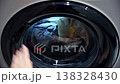 closing the Laundry machine door view showing clothes being washed in washing cycle 138328430