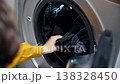 Person loading dark clothes into washing machine, laundry process in action 138328450