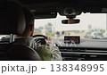 Inside view of a moving car driven man through a city. Urban street and pedestrians ahead. 138348995
