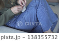 Close-up of a woman crocheting with yarn while sitting comfortably on a couch at home. Relaxed 138355732