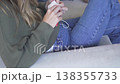 Woman crocheting with yarn while relaxing on a sofa at home. Cozy lifestyle scene highlighting 138355733