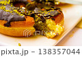 Eating Dubai-style donuts with chocolate glaze, topped with chopped pistachios 138357044