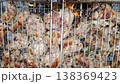 Pieces of meat, clamped in a metal grate and grilled over coals. The meat is covered in a marinade with herbs and spices. Gray, hot coals are visible from below. 138369423