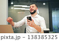 Bearded Man Celebrates Exciting News on Smartphone 138385325
