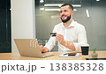 Happy young businessman using credit card for online shopping on laptop 138385328
