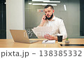 Focused Professional Male Talking on Phone, Reviewing Documents 138385332
