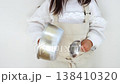A child wearing a large apron sloppily is making noise with a pot and ladle (5 years old, girl, Japanese) 138410320