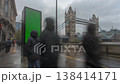 A green screen billboard stands on a rainy London street with Tower Bridge in the background. 138414171