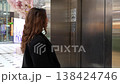 Side camera view of woman pressing elevator call button and waiting near stainless steel lift doors in modern shopping mall interior. Urban mobility, accessibility and daily routine 138424746