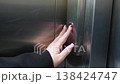 Close up of woman hand pressing elevator call button on stainless steel panel with indicator light turning on. Urban access, technology and daily routine concept 138424747