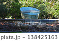 Low angle view centers a blue glass pavilion on a circular pool in Hiroshima, Japan. Water spills over the rim as stones and brick fragments sit in bright daylight. 138425163