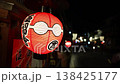 Close up red lantern with black kanji and white motifs hangs in Kyoto. Smaller lanterns and pedestrians move along dark street. Shallow depth and strong bokeh. 138425177