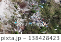 Aerial view overhead view of illegal dump site with mixed household, construction debris and plastic waste on grassy slope. 138428423