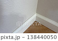 A clean corner of a room shows freshly installed baseboards with no visible seam or gap. The floor is wood-style, and the lighting highlights the crisp finish of the molding work. 138440050