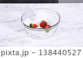 Two hands carefully place a transparent glass plate onto a white marble countertop. The camera is static and framed overhead, emphasizing clean lines and minimal movement. Lighting is soft and even 138440527