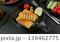 Grilled halloumi cheese in a black pan with olives, tomatoes, cucumbers, thyme and lemon. Traditional cheese of the Eastern Mediterranean. Black background, selective focus, close-up. 138462775