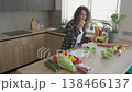 Woman Tasting Fresh Green Salad In Modern Home Kitchen 138466137
