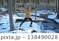 Man practicing yoga pose in winter forest near frozen stream 138490028
