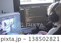 A teenage boy learns programming while working at a desktop computer, writing code on a monitor in a 138502821