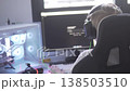 A teenage boy sits at a computer in a modern home setup, learning programming and typing code while 138503510