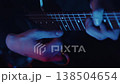 Close up of a guitarist's hands playing riffs on the neck of an electric guitar under colorful blue and red stage lights 138504654