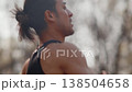 Athletic man breathes deeply while running in place outdoors on a sunny day. Surrounded by trees, he showcases energy and determination in a vibrant summer setting 138504658
