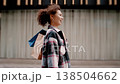 Young woman enjoying a successful shopping spree walks down the street, cheerfully carrying colorful shopping bags over her shoulder, radiating happiness and satisfaction 138504662