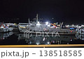 Nighttime video taken from a boat showing a brightly lit, large industrial ship or vessel anchored in the dark harbor waters of the Andaman Islands. 138518585