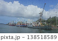 Video shot from a boat showing a port with cargo ships, cranes, and docked vessels along the coast of the Andaman Islands under cloudy skies. 138518589